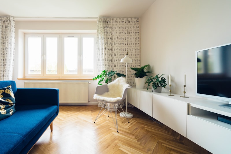 A neutral patterned area rug anchoring a living room seating arrangement on a wood floor