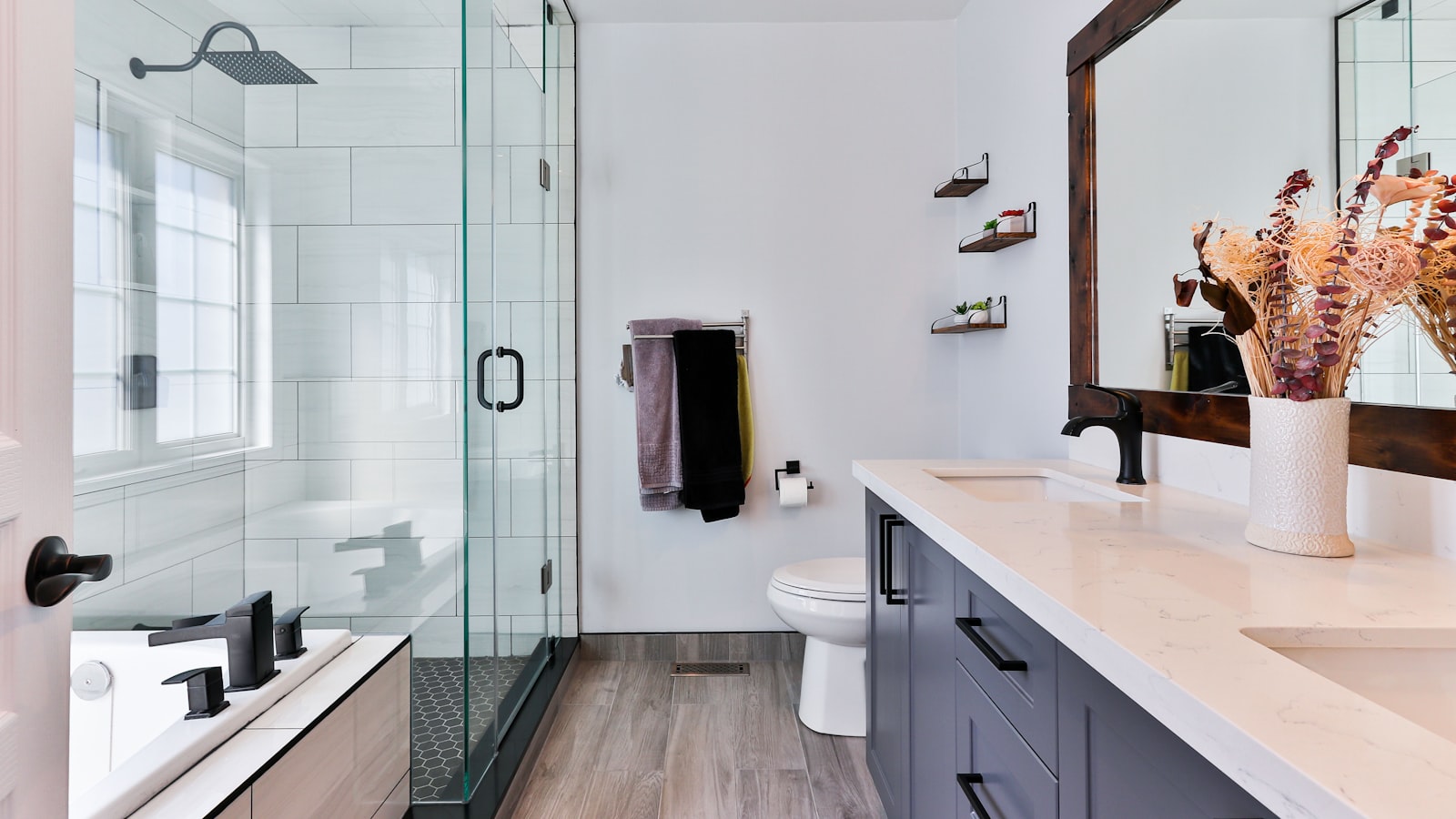 A compact modern bathroom with a round mirror, wall sconce, and floating vanity